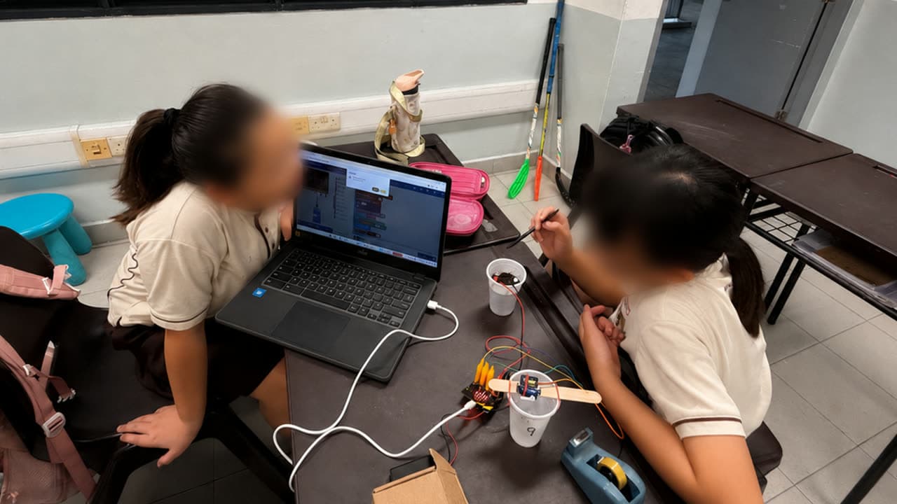 Two students collaborating on the build at a workstation